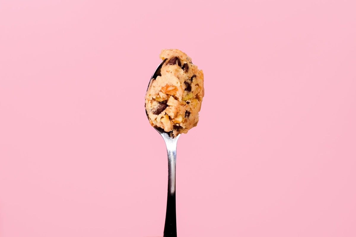A spoon of cookie dough on a pink background