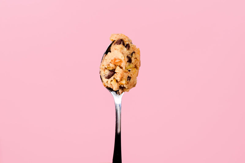 A spoon of cookie dough on a pink background