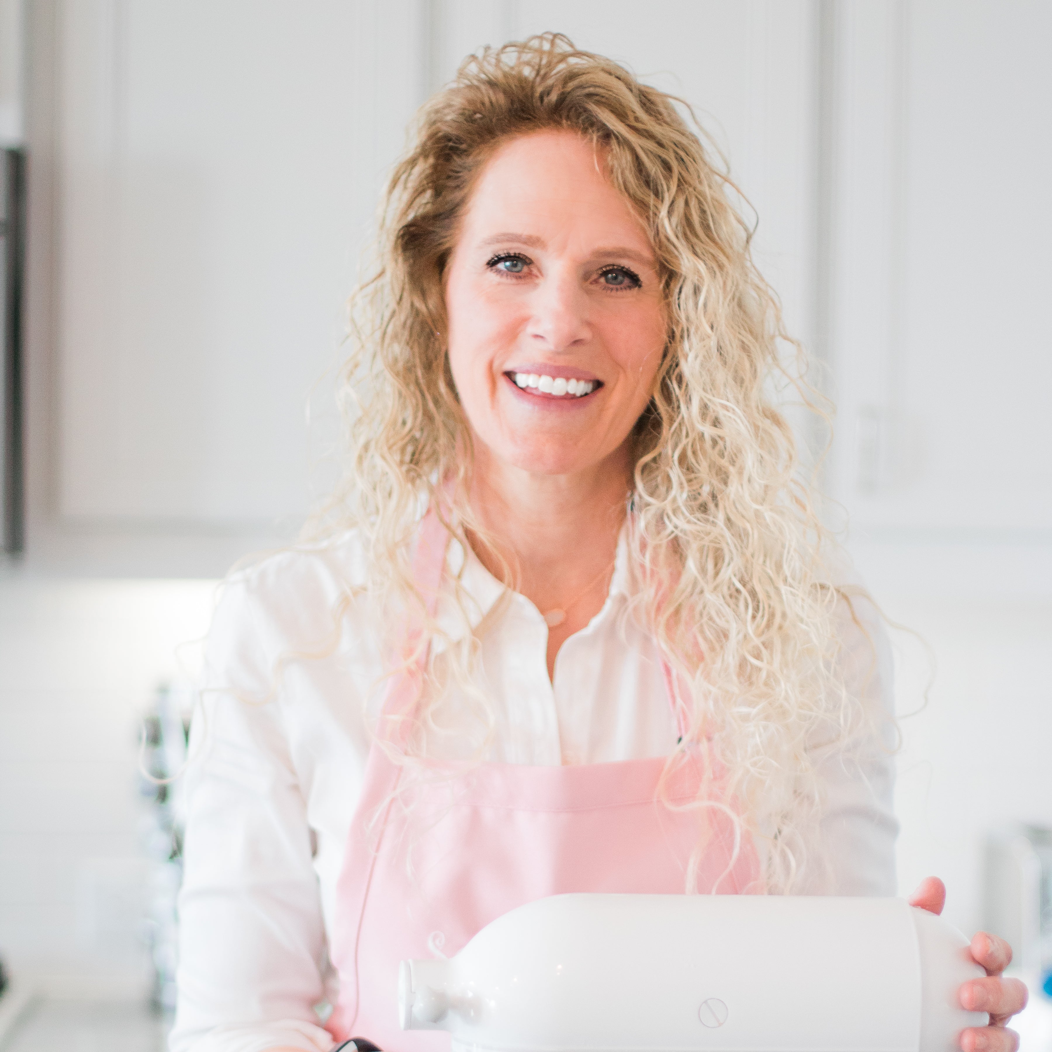 A woman standing in a kitchen operating a mixer
