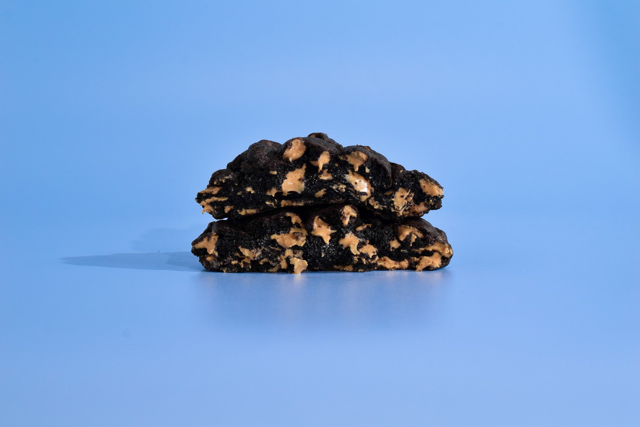 Two cut open Peanut butter cookies stacked on a blue background.