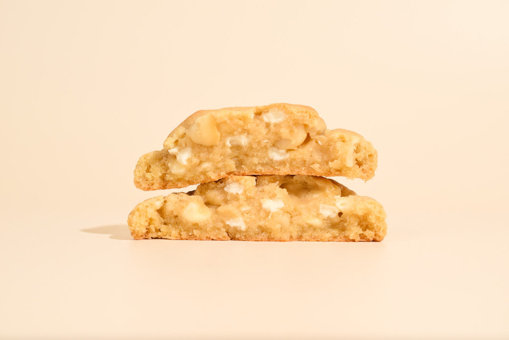 Two stacked caramel macadamia cookies on a cream background