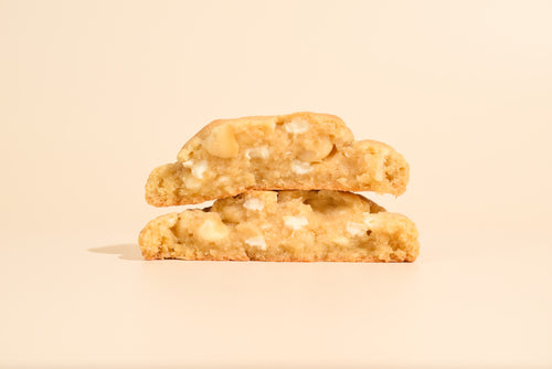Two stacked caramel macadamia cookies on a cream background