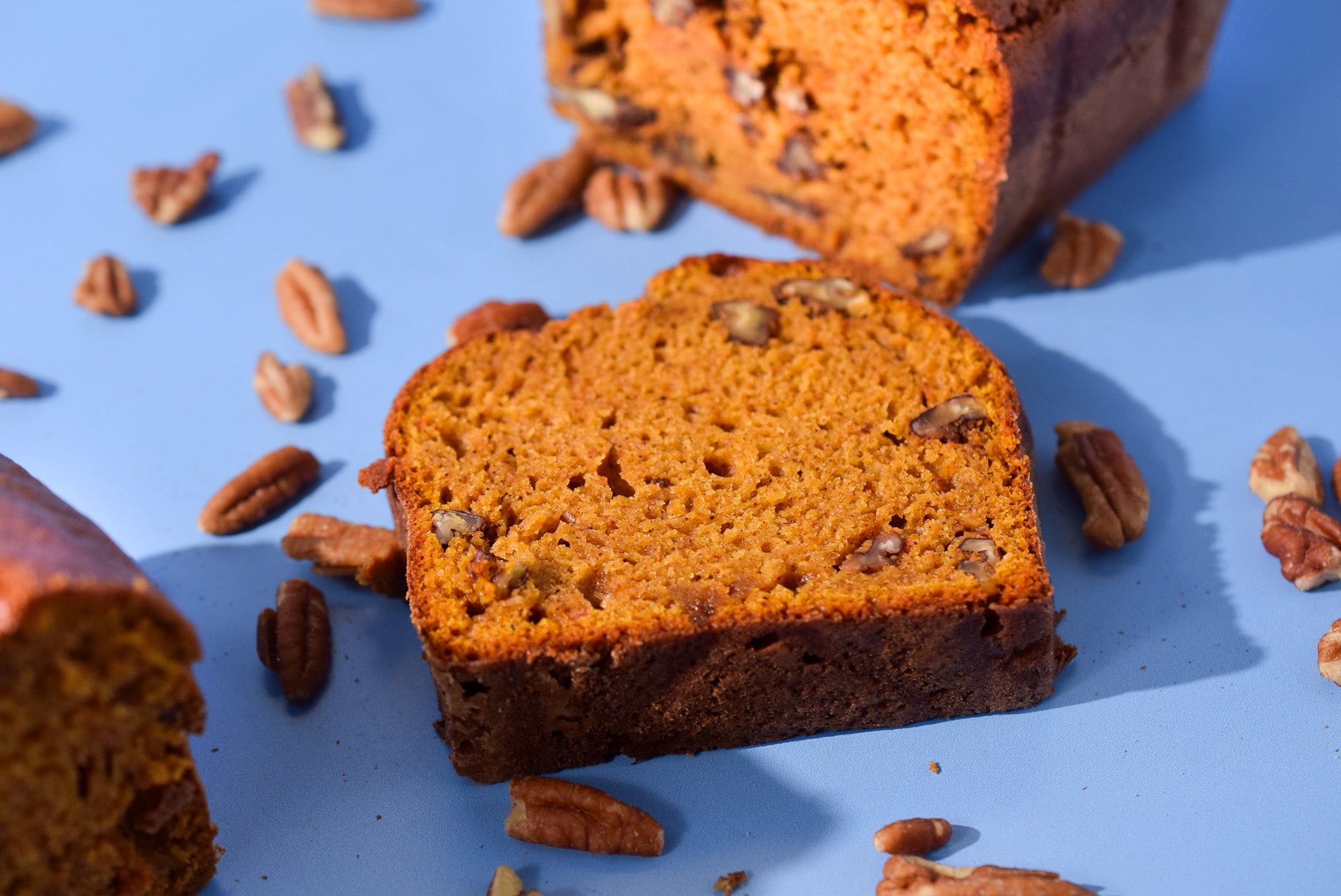 Sliced pumpkin bread with pecans on a blue background
