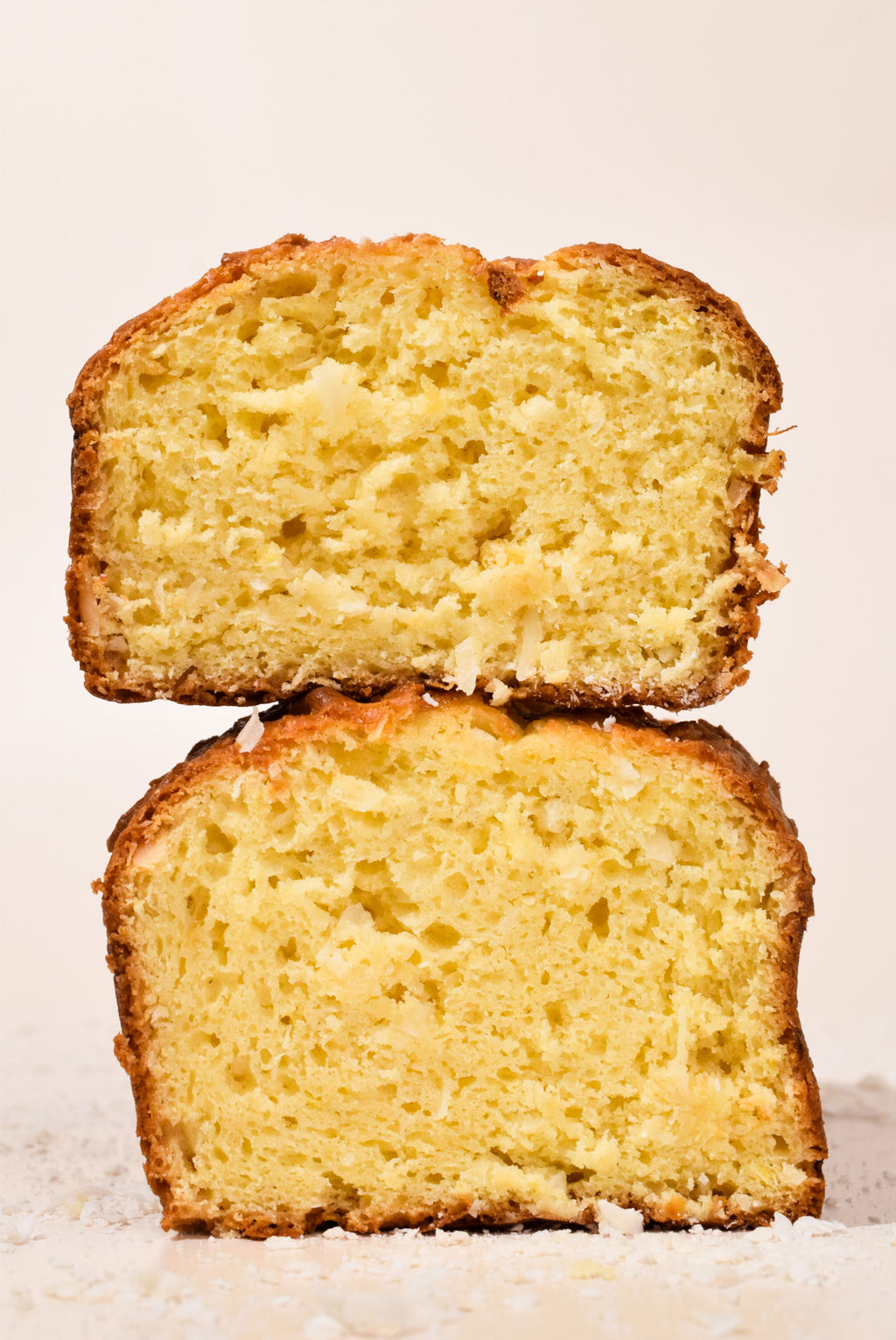 Two slices of Hawaiian Coconut Loaf stacked on a white background