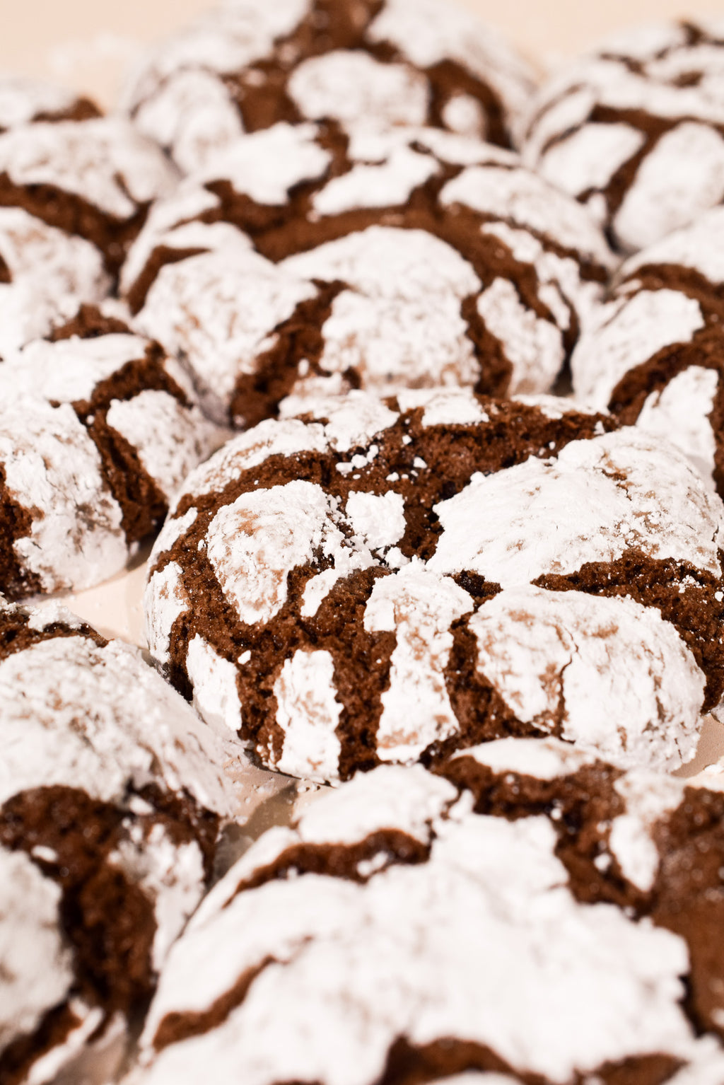 A close-up shot of chocolate crinkle cookies dusted with powdered sugar, filling the frame.