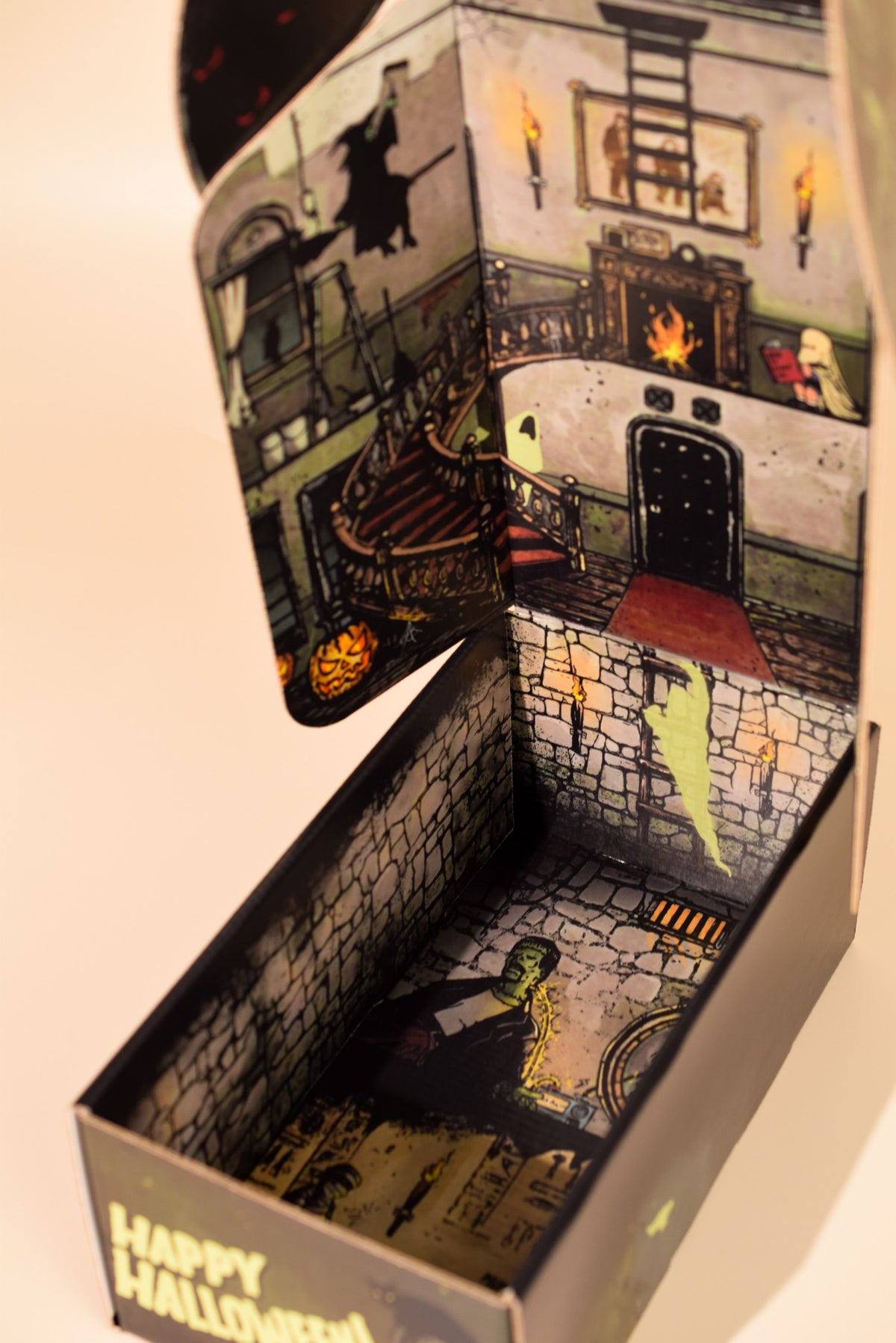 An open spooky Halloween gift box showing monsters living in a haunted house.