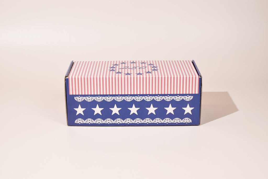 Box with red and white striped top and blue base with white stars on a beige background