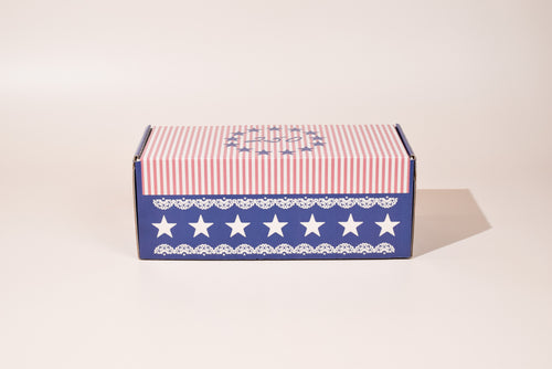 Box with red and white striped top and blue base with white stars on a beige background