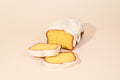 Keksi Iced Lemon Loaf with stacked slices on a cream background.