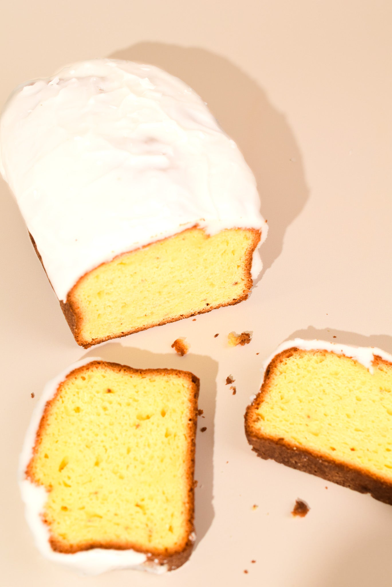 An over the top image of the Keksi Lemon Loaf with two slices on a cream background.