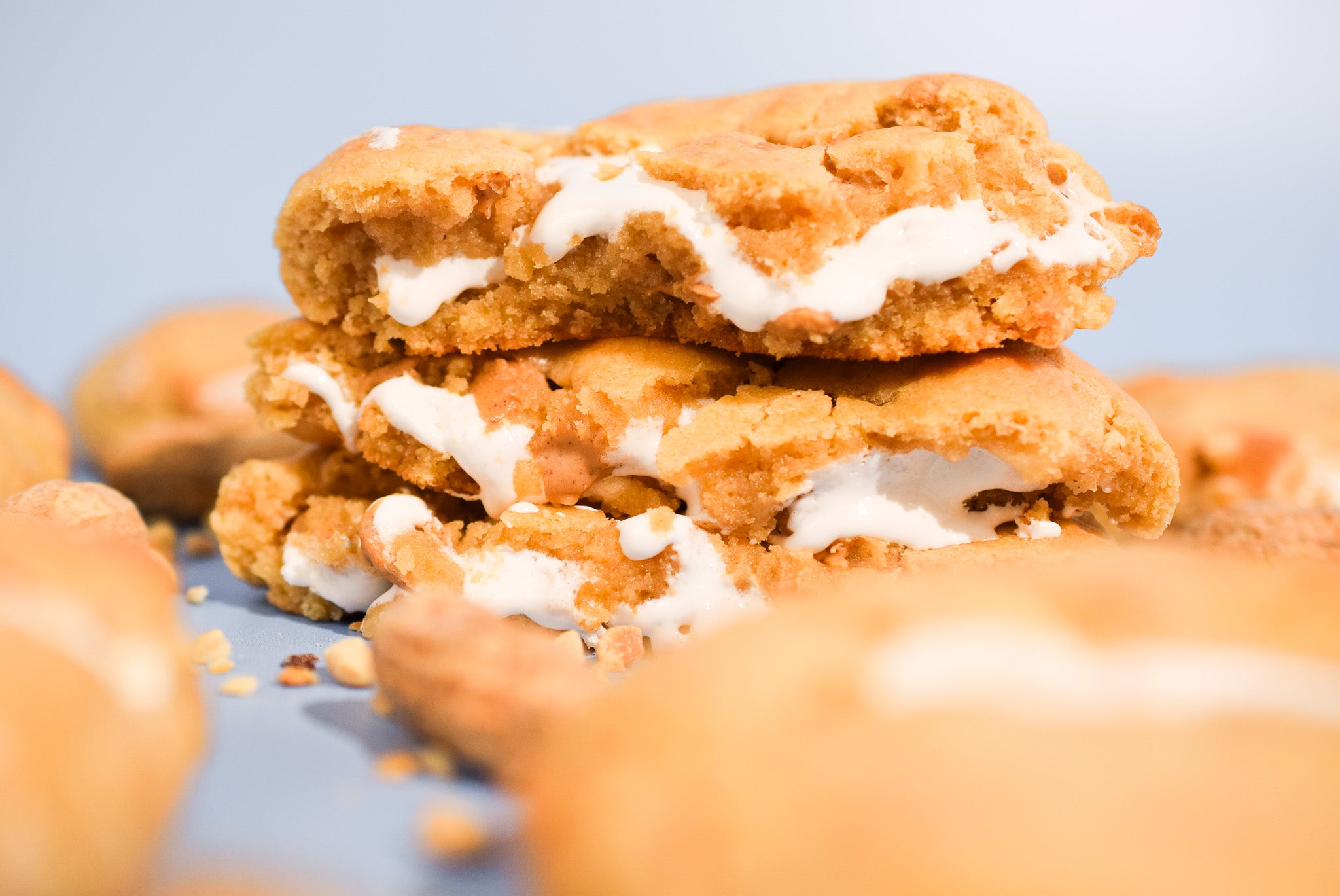 A stack of Peanut Butter Marshmallow cookies with scattered crumbs on a blue background.