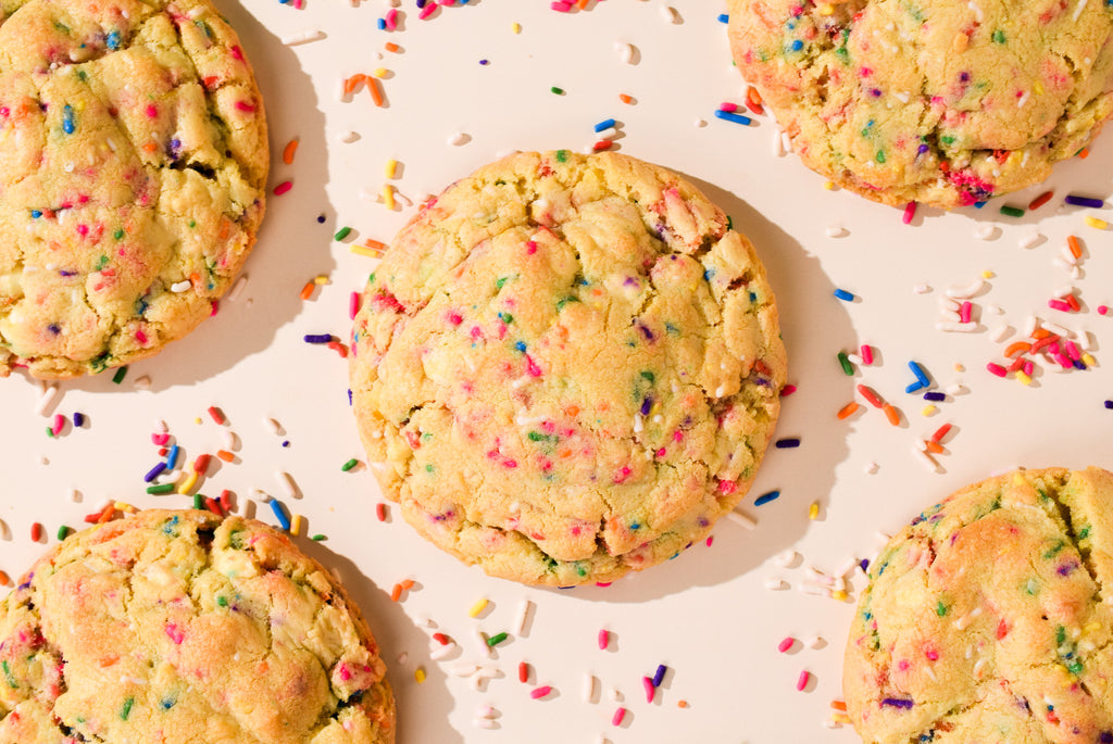 An overhead shot of Birthday Cake cookies with scattered rainbow sprinkles.
