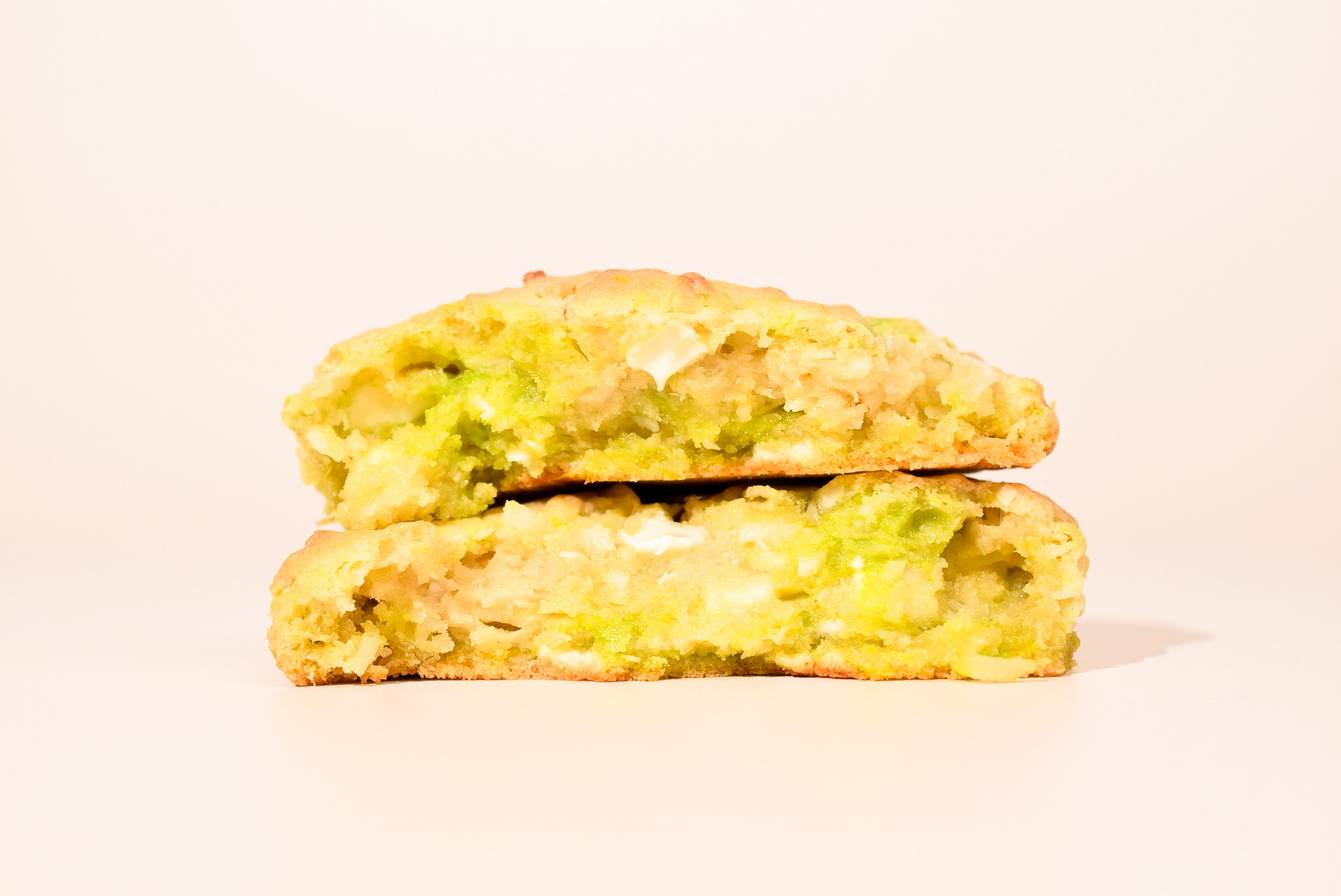 Two Key Lime Coconut Cookies stacked on a cream background.