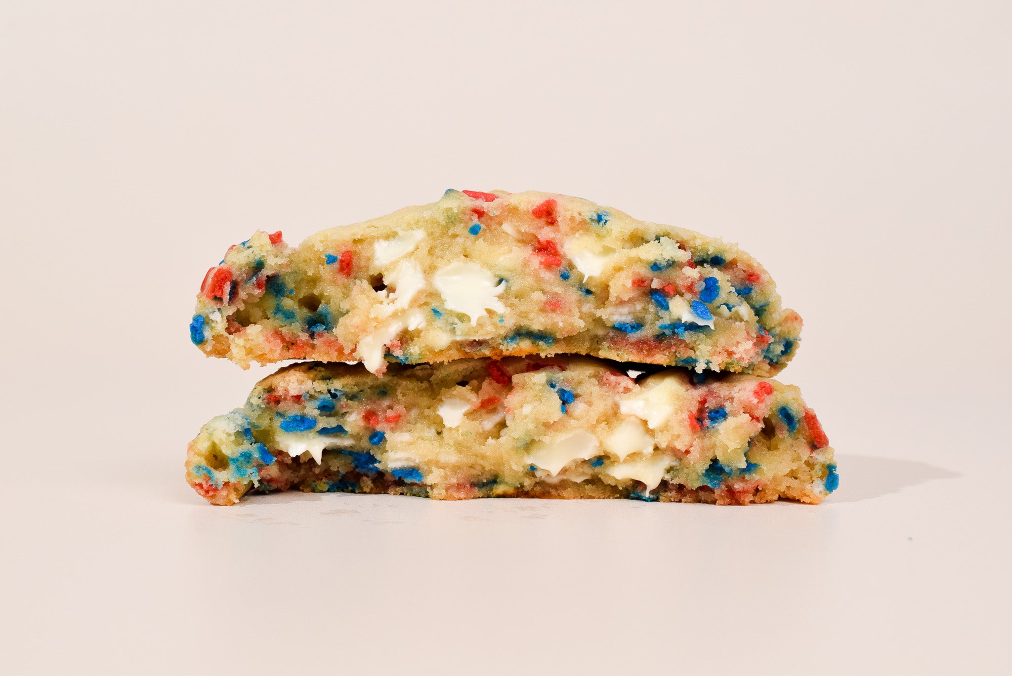 Half-eaten cookie with colorful sprinkles on a beige background