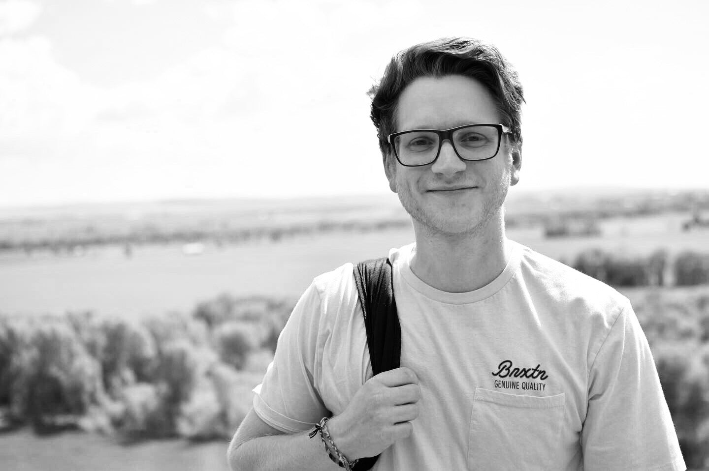 Person wearing a t-shirt with a brand logo against a scenic background