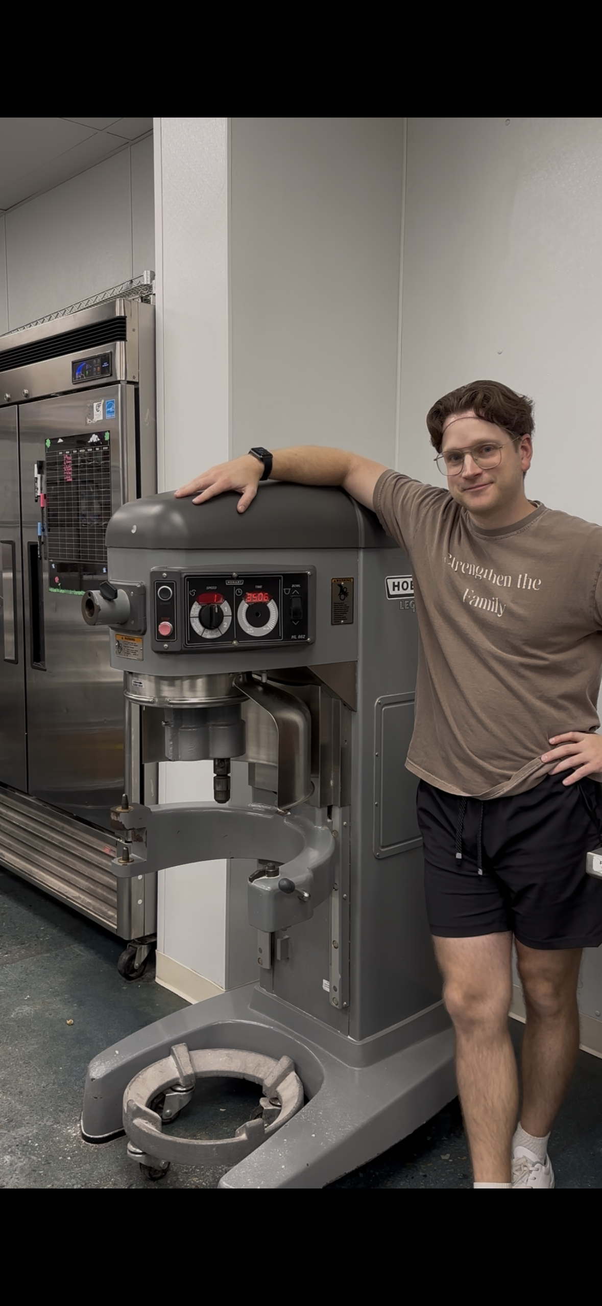 Person standing next to a large industrial machine in a kitchen setting