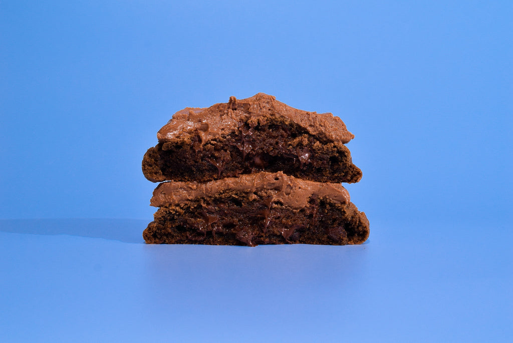 Two cut open Texas Sheet Cake cookies stacked on a blue background.