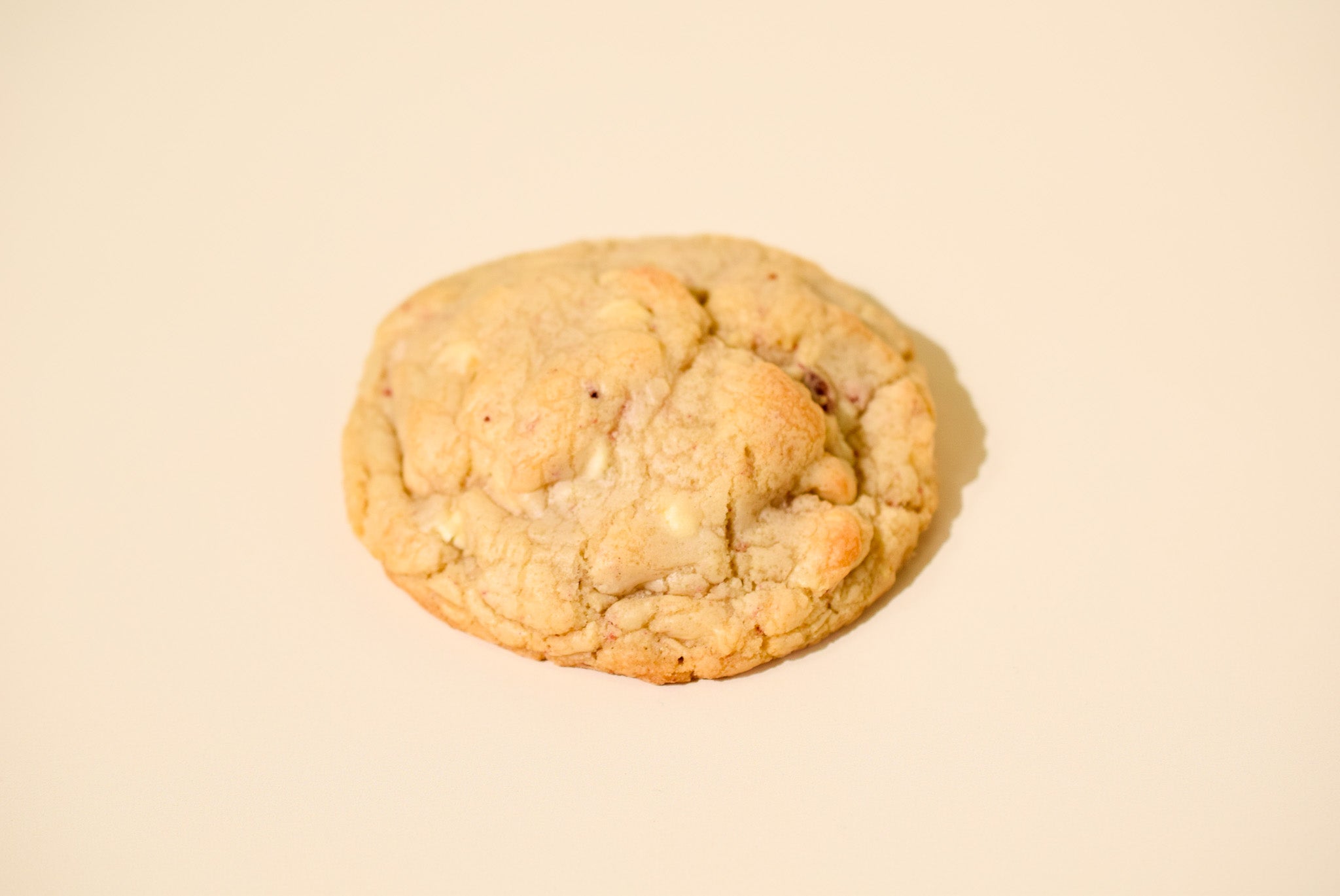 A White chocolate strawberry cookie on a cream background.