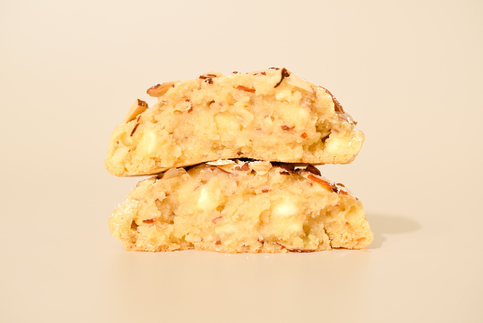 Two Almond Croissant cookies stacked on a cream background.