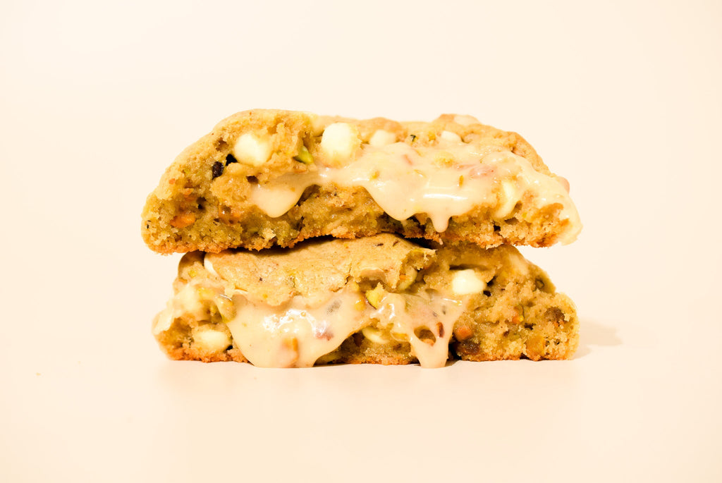 Two stacked honey pistachio cookies on a cream background.