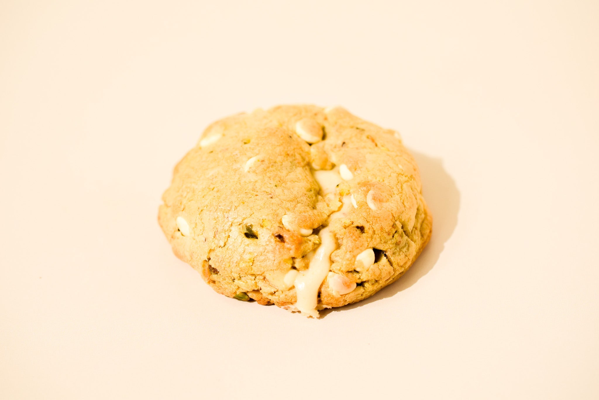 A Honey Pistachio cookie on a cream background.