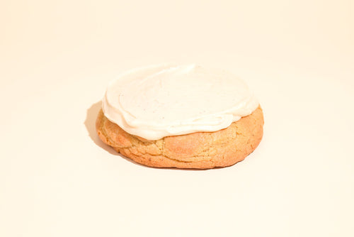 Keksi Pumpkin cookie under a thick layer of white icing, cream background